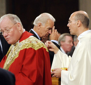V. P. Biden blesses himself after receiving communion at St. Patrick's.  Cardinal Dolan looks the other way.